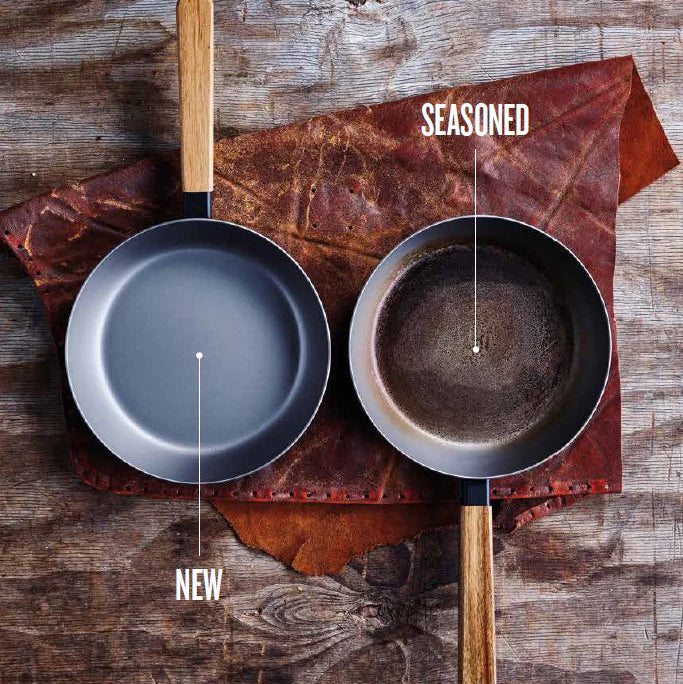 Two frying pans, one new and one seasoned, on a wooden surface